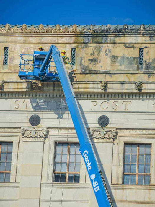 Blue cherry picker lift against a large building with 'State Post' inscription.