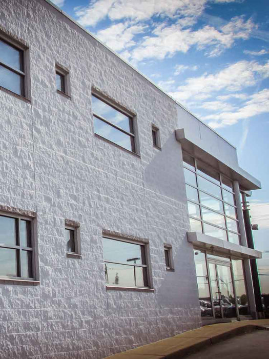Modern building with white textured facade and glass windows under a blue sky.