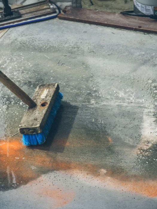 Cleaning brush with blue bristles on a concrete floor
