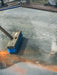 Cleaning brush with blue bristles on a concrete floor