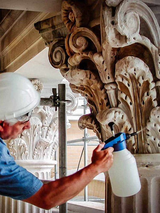 Person using a spray bottle on ornate architectural details