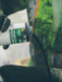 Person holding a bottle of Integral Color black ink cartridge with a blurred green background