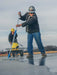 Two workers on a rooftop using tools to prepare a surface for construction.