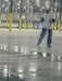 Person cleaning a large industrial floor with a wet mop in a warehouse setting.