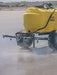 Yellow agricultural sprayer on a field with dust or smoke in the foreground