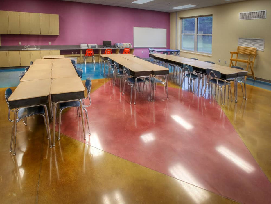 School cafeteria with tables, chairs, and a sink.