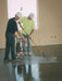 Two workers using floor grinding equipment on a concrete floor.