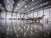 Large airplane inside a spacious hangar with high ceilings and large doors.