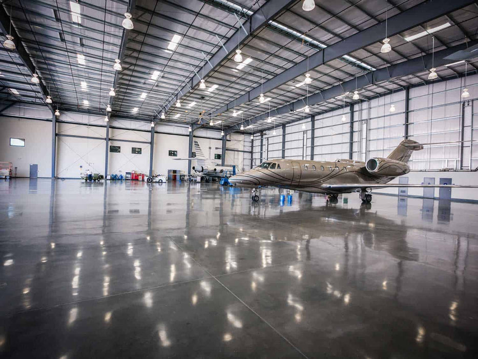 Large airplane inside a spacious hangar with high ceilings and large doors.