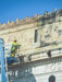 Person on a lift cleaning the exterior of a building with ornate architecture.