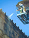 Person on a lift cleaning the top of a building with a blue sky background