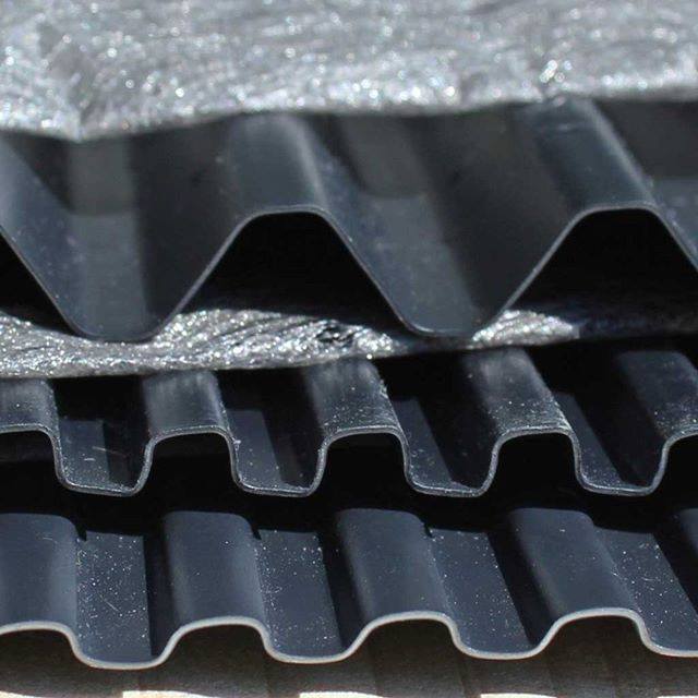 Stack of corrugated black plastic sheets with metallic surface