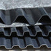 Stack of corrugated black plastic sheets with metallic surface