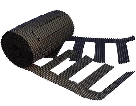 A roll of black vent mat with weep holes for block basement walls, accompanied by several spread-out pieces of the mat.