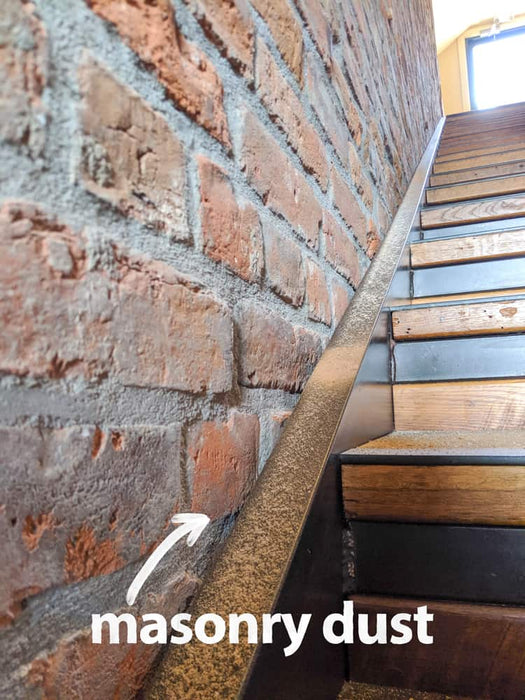 Wooden staircase with masonry dust on a brick wall