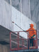 Person in orange hoodie cleaning a marble wall with a long-handled tool on a lift.