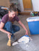 Person cleaning up small items in a garage with a broom and dustpan.
