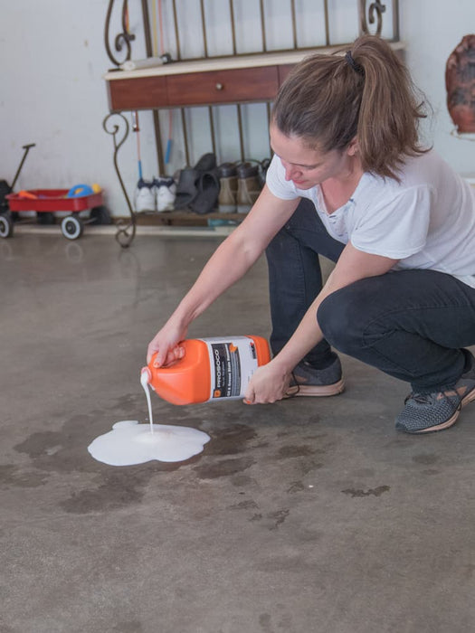 Person applying white liquid from a container onto a concrete floor.