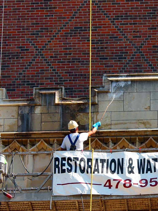Person working on a building with a 'Restoration & Wat' banner in the foreground.