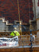 Construction worker on a scaffold with waterproofing banner in front of a brick wall.
