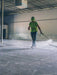 Person in a warehouse using a pressure washer on a concrete floor