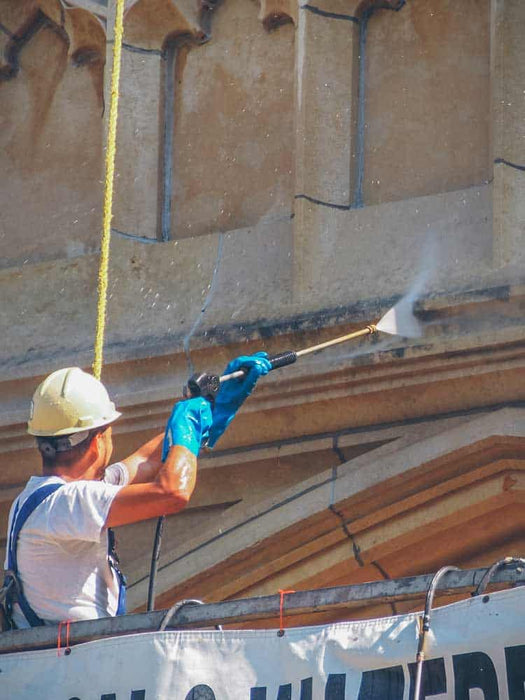 Person in hard hat and safety gear applying material to a wall