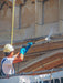 Person in hard hat and safety gear applying material to a wall