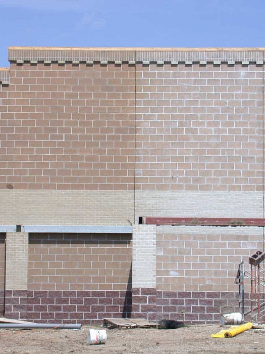 Brick wall with a section of concrete and a blue sky above