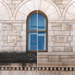Stone wall with an arched window and blue sky reflection