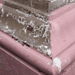 Close-up of a corner where pink and brown materials meet, with peeling paint.